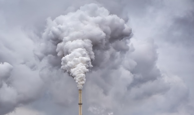 Foto el humo de la pipa de fábrica contra el oscuro cielo nublado