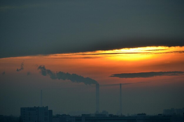 Humo procedente de la chimenea de la fábrica al atardecer