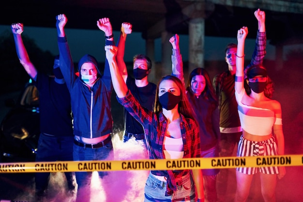 Foto humo puños policía grupo de jóvenes que protestan que se unen activista por los derechos humanos o contra el gobierno