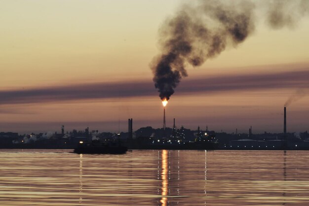 Foto el humo que emite la fábrica contra el cielo durante la puesta del sol