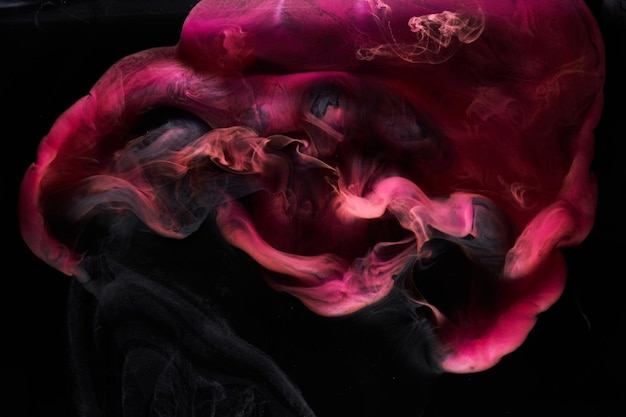 Humo rosa sobre fondo de tinta negra, niebla colorida, abstracto remolino toque mar océano, pigmento de pintura acrílica bajo el agua
