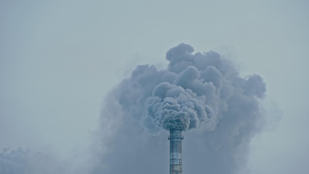 Este humo saliendo de la chimenea de una fábrica. Emisiones nocivas a la atmósfera, desde la tubería. Daños graves al medio ambiente. Pila de planta Estación de carbón. Fotografía de cerca. Vista oscura y triste.