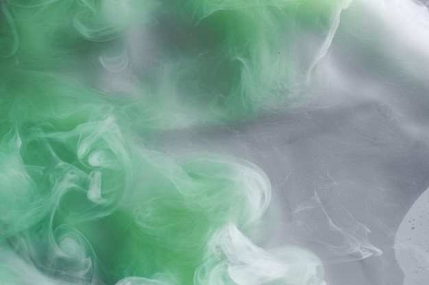 Humo verde sobre fondo de tinta blanca niebla colorida remolino abstracto esmeralda océano mar pintura acrílica pigmento bajo el agua