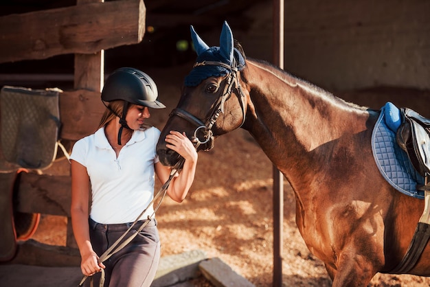 Humor alegre. Amazona no capacete protetor uniforme e preto com seu cavalo.