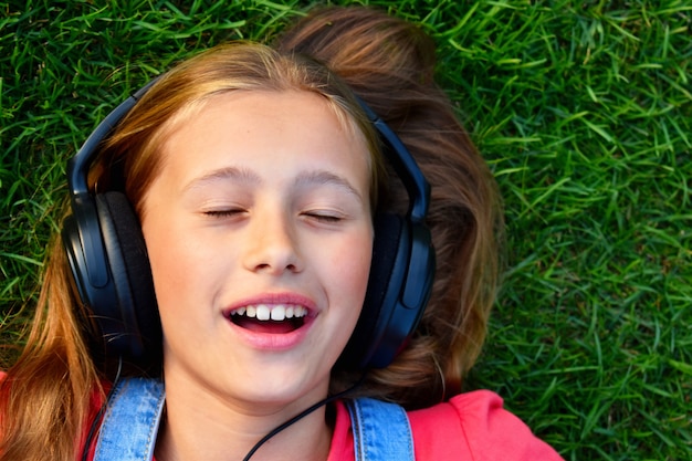 Humor alegre musical. Una niña se encuentra en la hierba y escucha música en los auriculares.