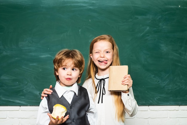 Humor feliz sorrindo amplamente na escola educação crianças na lição da escola menina e menino com expressão de rosto feliz perto da mesa com material escolar conceito escolar