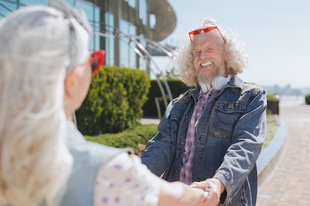 Humor positivo. Anciano alegre sonriendo mientras sostiene las manos de su esposa