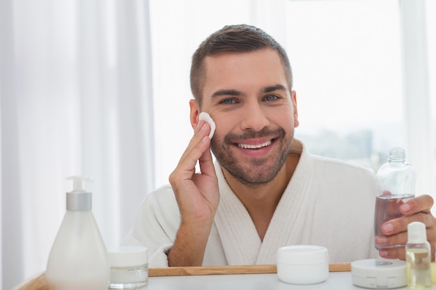 Foto humor positivo. homem alegre e feliz sorrindo enquanto limpa o rosto