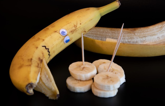 Foto humorvolles foto, umgekippte banane betrachtet die bananen, in scheiben geschnitten und bananenschale