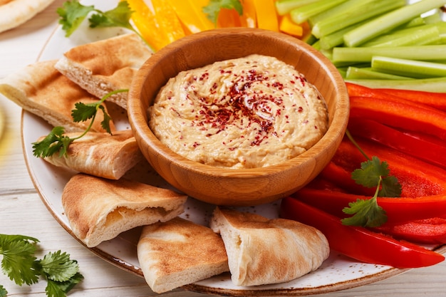 Húmus caseiro saudável com legumes frescos variados e pão pita.