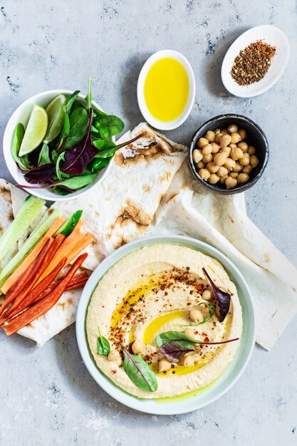 Humus clássico em uma tigela com ervas, páprica defumada, azeite e alface