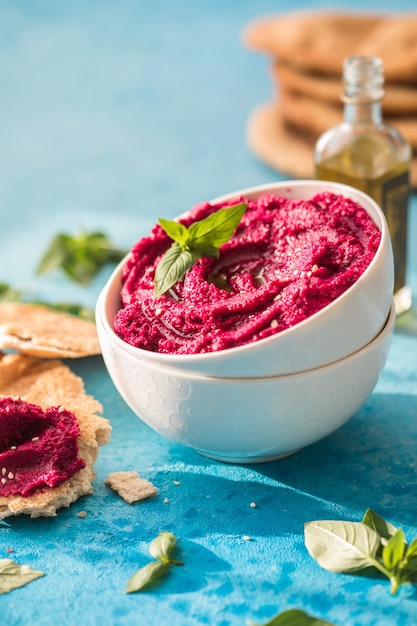 Humusschale. Rote-Bete-Hummus mit frischem Gemüse, Olivenöl auf dem Tisch