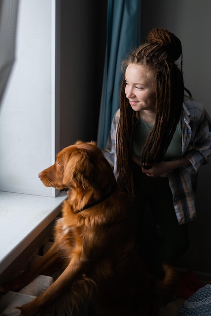 Foto hund und besitzer blicken auf das fenster zu hause nova scotia duck toller retriever