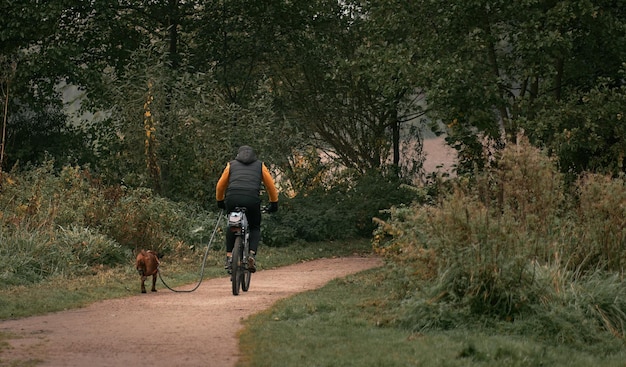 Hund und Fahrrad Rückansicht eines Mannes, der Fahrrad fährt, während sein Hund in seiner Nähe läuft