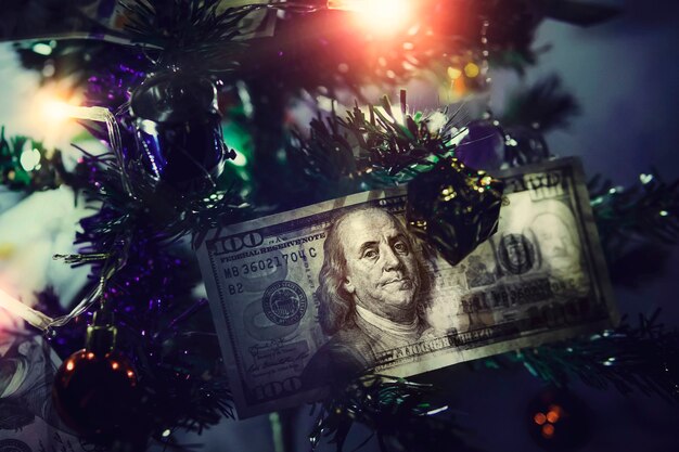 Hundert-Dollar-Scheine. Geld am Weihnachtsbaum. Kleiner verzierter Weihnachtsbaum auf blauem Hintergrund.