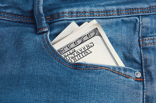 Foto hundert-dollar-scheine sind in der gesäßtasche seiner blue jeans in zwei hälften gefaltet.