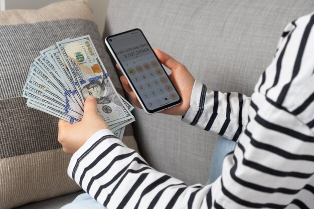 Foto hundertdollarscheine und ein smartphone in den händen einer person