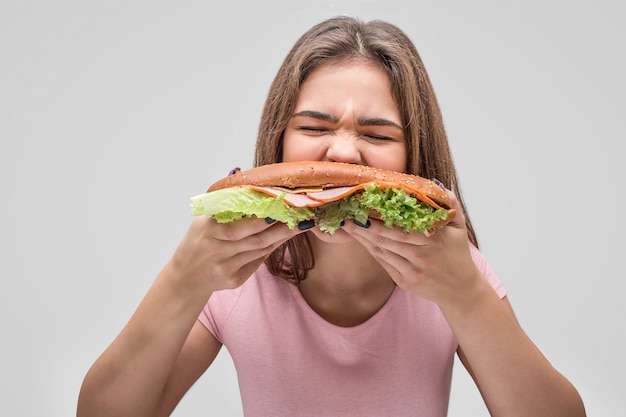 Hungrige junge Frau beißt Burger