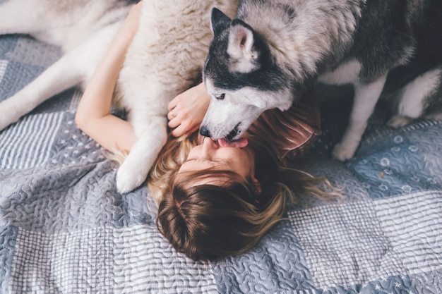 Husky filhote lambendo o rosto de sua dona.