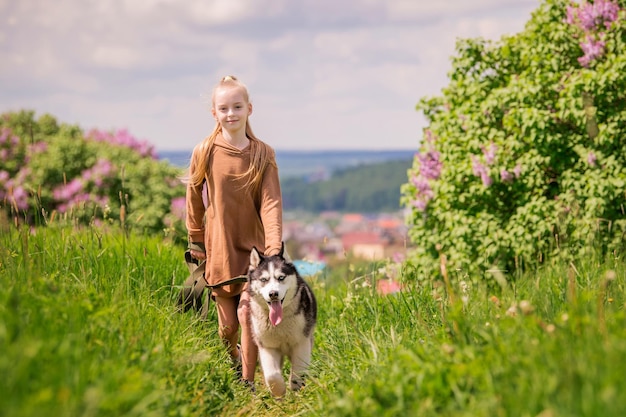 El husky siberiano y su dueño corren alegremente a lo largo de la carretera juntos en el contexto de un paisaje rural panorámico en verano