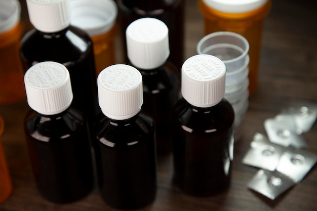 Foto hustensirupflaschen, medikamentenbecher, offene medikamentenblisterverpackungen und medikamentenflaschen auf einem tisch