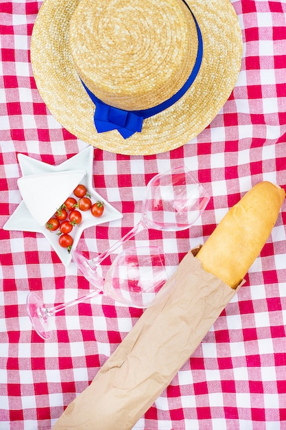 Hut, Gläser, Brot und Käse auf roter Tischdecke