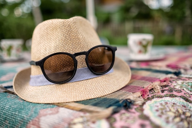 Hut und Sonnenbrille auf Sommertisch im Freien