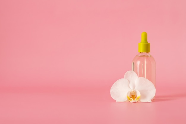 Hyaluronsäure in einer Glasflasche mit Pipette mit Orchideenblüte isoliert auf rosa Hintergrund mit Beschneidungspfad Flüssiges Gel oder Serum Hautpflegekosmetik