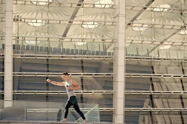 Hydratation Vitalität Training an der frischen Luft Die Pose einschlagen Befreien Sie Ihren Geist bei sportlichen Aktivitäten Junger Mann bereitet die Muskeln vor dem Training vor und hält eine Flasche Mineralwasser in der Hand