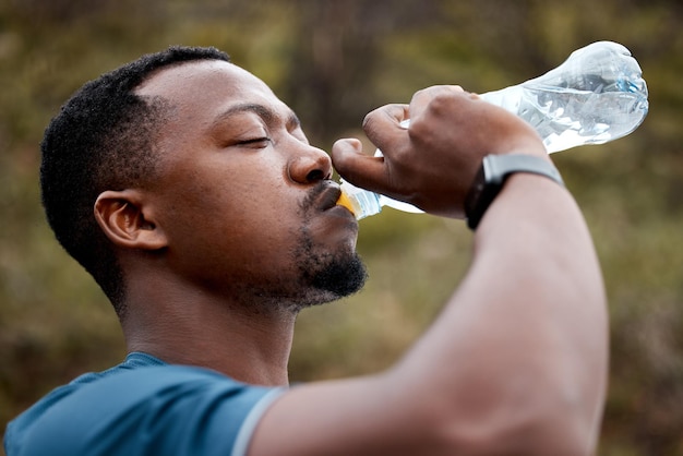 Hydratisiert zu bleiben kann Ihr Training verbessern Aufnahme eines sportlichen jungen Mannes, der Wasser trinkt, während er im Freien trainiert