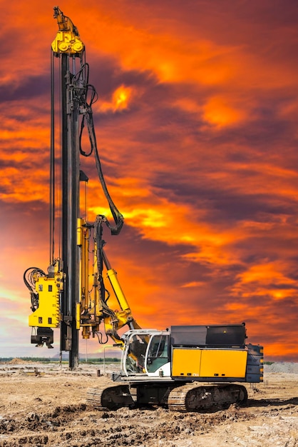 Hydraulische Bohrmaschine auf der Baustelle macht Pfähle Pfahlfeld Modernes Bohrgerät Pfähle gegen den Sonnenuntergang Arbeitsbohrgerät unter schwierigen Bedingungen