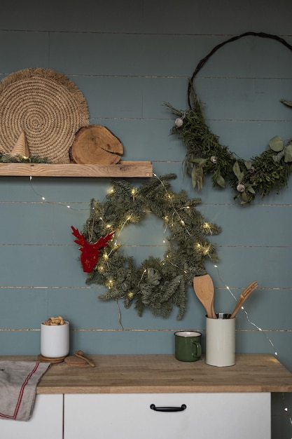 Hygge nórdico escandinavo estilo cozinha em casa design de interiores com decorações de Natal Mobiliário de cozinha utensílios de cozinha de madeira aconchegante Guirlanda de Natal pendurada na parede azul empoeirada