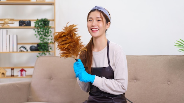 Hygiene-Reinigungskonzept Hausmädchen trägt Handschuhe und hält den Staubwedel zur Hausreinigung