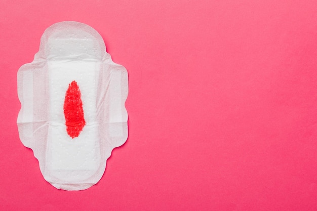 Foto hygieneprodukte für frauen oder damenbinden mit roter feder auf farbigem hintergrund pastellfarbe nahaufnahme leerer platz für text weibliche tägliche hygiene