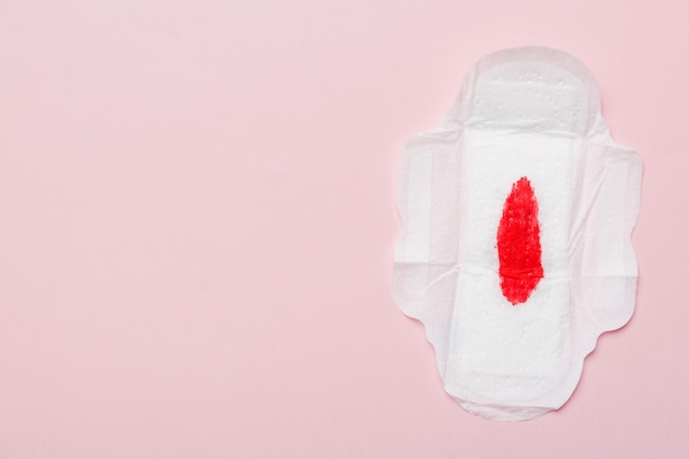 Hygieneprodukte für Frauen oder Damenbinden mit roter Feder auf farbigem Hintergrund Pastellfarbe Nahaufnahme Leerer Platz für Text Weibliche tägliche Hygiene