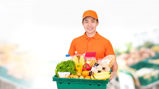 Hygienischer lächelnder asiatischer Mann, der Supermarktlebensmittelbehälterbox anbietet, der Hauslieferdienst anbietet