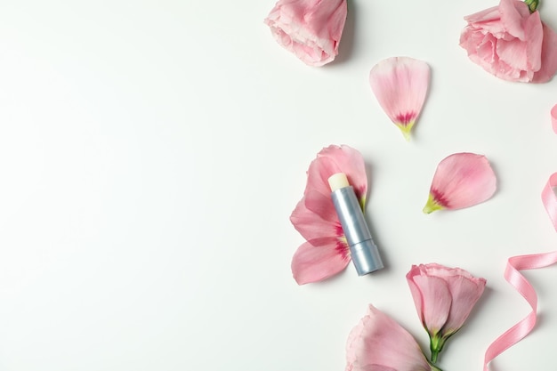 Hygienischer Lippenstift und Rosen auf weißem Hintergrund