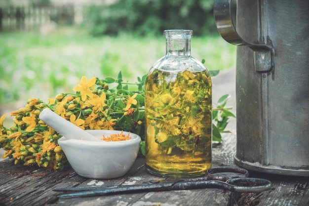 Hypericum Johanniskraut pflanzt Öl oder transparenten Flaschenmörser auf Holztisch