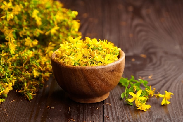 Hypericum perforatum o St Johns wort capullos de flores en un tazón de madera