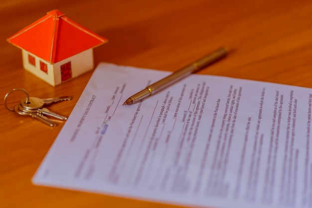 Hypothekenvertrag für den Verkauf von Immobilien mit einem Stift und Hausschlüsseln