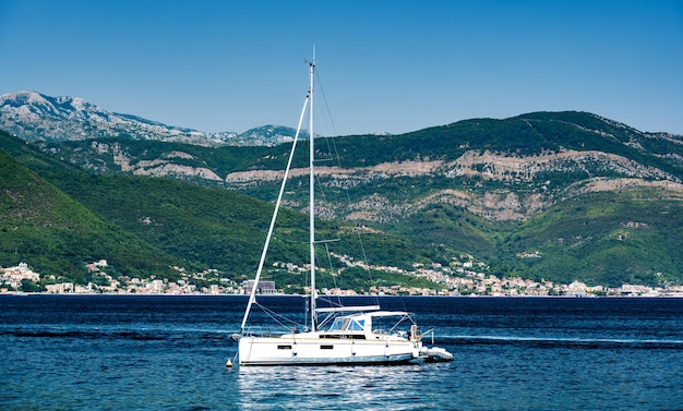 Iate branco no mar Adriático montenegro com belas montanhas e floresta em barco de luxo de fundo em ...