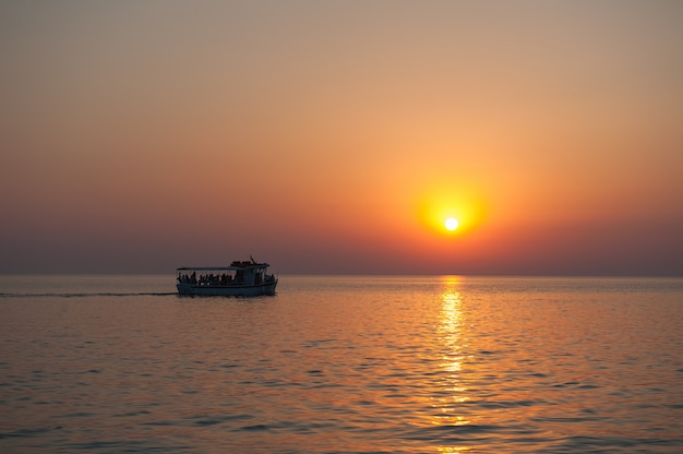 Iate com turistas ao pôr do sol com pássaros voando para longe