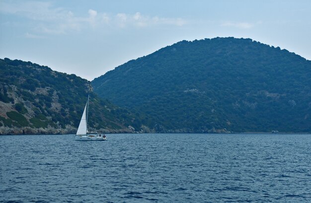 Iate navega no mar ao longo das montanhas