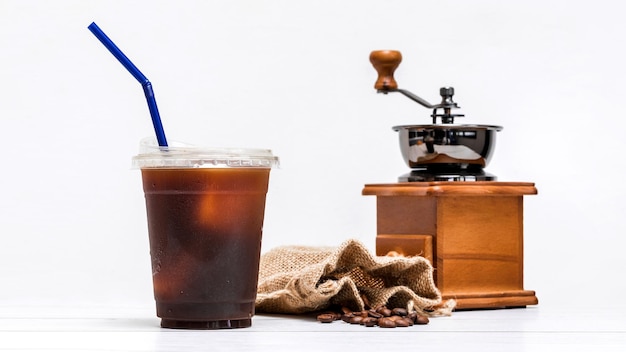 Ice Americano Kaffee in einer Tasse mit Vintage Kaffeebohnenmühle und Kaffeebohnensackbeutel