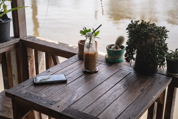 Ice latte y teléfono en la mesa al lado del río