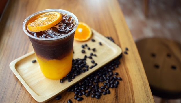 Iced Coffee Getränkekarte Orange Americano mit frischen Orangenfrüchten gemischt in einem Plastikbecher Auf dem Holz