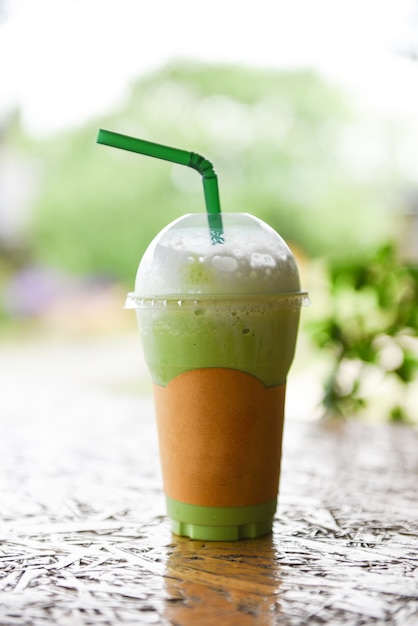 Foto iced drinks grüntee-smoothie - matcha-grüntee mit milch auf plastikglas