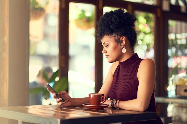 Ich bin frei, mich jetzt zu treffen, wenn du magst Schnappschuss einer attraktiven jungen Frau, die in einem Café eine SMS auf ihrem Handy schreibt