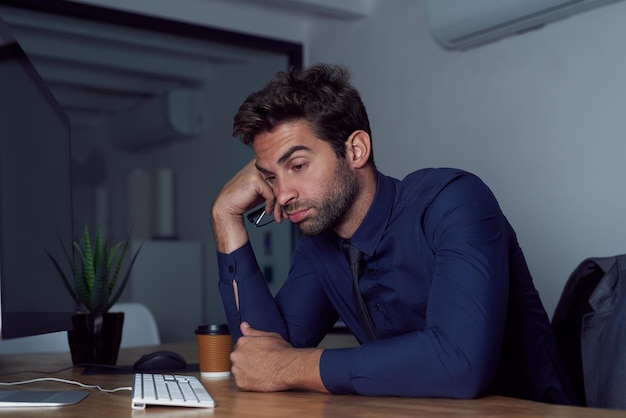 Ich brauche eine Pause Portrait eines müde aussehenden jungen Geschäftsmannes, der an seinem Schreibtisch sitzt