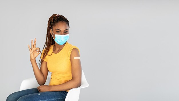 Ich empfehle Coronavirus-Impfstoff junge schwarze Dame in Gesichtsmaske, die gegen das Auftreten von Covid-Viren geimpft ist